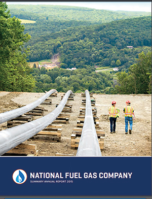 The cover of National Fuel Gas’ 2015 annual report shows a pipeline running directly into a scenic rural town and two helmeted workers walking along it for perspective.